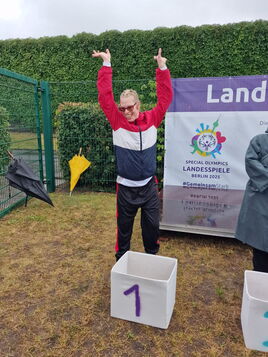Freudige Athletin Sandra hebt jubelnd stolz die Arme über dem Podest für den 1. Platz.