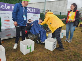Athlet Anton im Rollstuhl erhält freudig seine Medaille für Platz 5 bei Special Olympics.