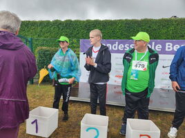Jorden und zwei weitere Athleten stehen stolz auf dem Siegerpodest draußen nach Wettkampf!