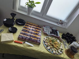 Ein Buffet mit Kuchen, belegten Broten und Pralinen auf gelber Tischdecke angerichtet.