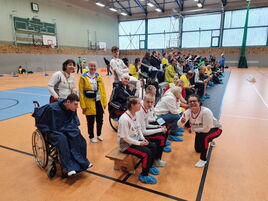 Athlet:innen und Betreuer:innen der Special Olympics auf dem Basketballfeld, einige lächeln.